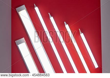 Set Of Neon Led Lamps. Saving Energy Lamps On A Red Ceiling.