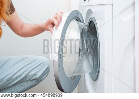 Washing Clothes. A Woman Is Loading A Washing Machine. Light Interior. Close-up. Woman Putting Cloth