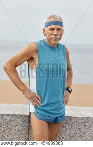 Caucasian Aged Man Wearing Sporty Top, Shorts And Sunvisor Cap Posing On Camera With Hands On Hips S