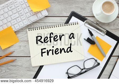 Refer A Friend. Text On Notepad Near Yellow Stickers.