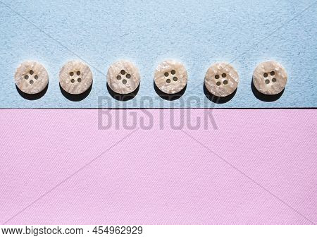 Monochrome Identical Sewing Buttons Composition On Pink And Blue.background. Flat Lay, Layout And Ta