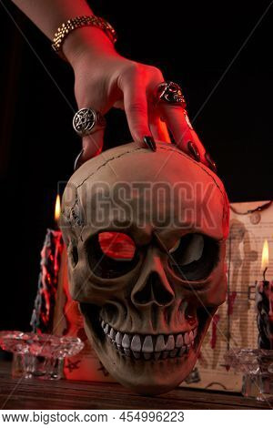 Vertical Shot Hand Over The Humans Skull On Black Background. Antichrist Satanic Ritual Concept.