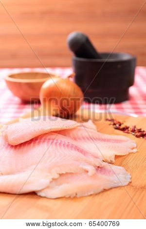 Raw fish tilapia on cutting board and spices