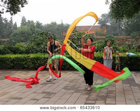 Beijing, China - Jul 17, 2011: Chinese Woman Doing Gymnastics With Ribbons In Jingshan Park. Tai Chi