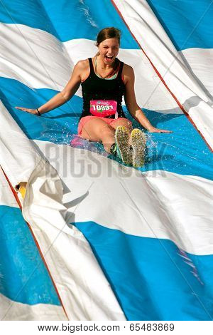 Young Woman Enjoys Going Down Slide In Obstacle Race