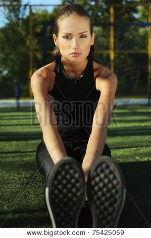 Young beautiful girl doing sport exercises in the street