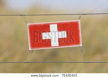 Border Fence - Old Plastic Sign With A Flag