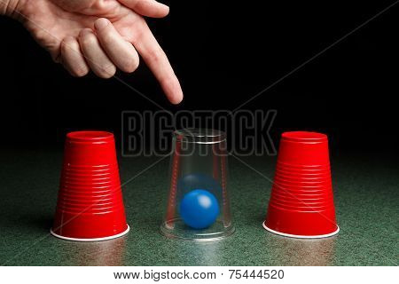 Blue Ball Under Clear Cup With Hand