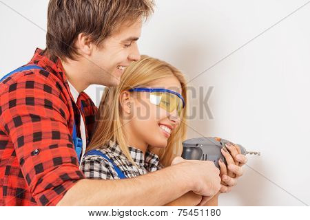 Smiling repairman helping woman to use drill