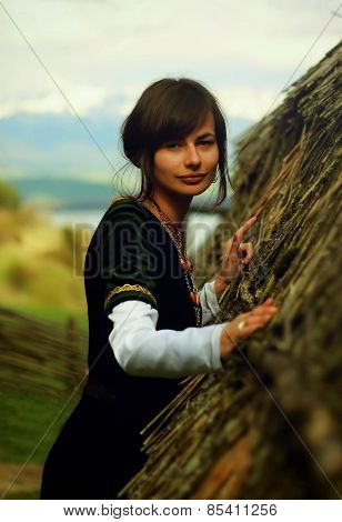 woman with dark hair black velvet historical dress and a subtle smile is touching gently