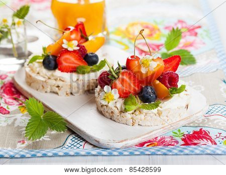 Multigrain rice cakes with berries, fruit and soft cheese for healthy breakfast