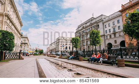 People resting, sitting on bench on Lenin Street in summer in Mi
