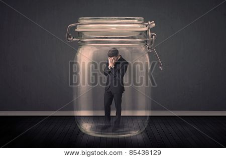 Businessman trapped into a glass jar concept on background