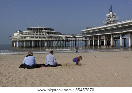 People Sitting In The Spring Sun Before The Pier Of Scheveningen