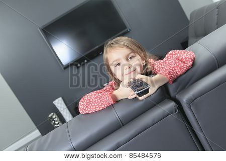 cute little girl with remote control in front of TV.