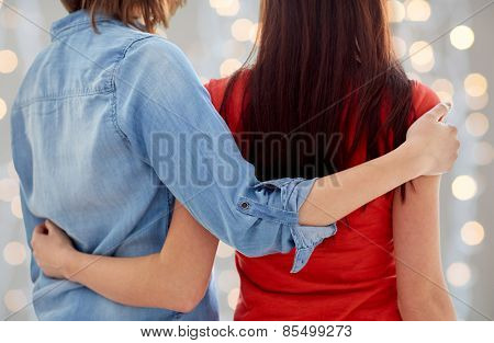 people, homosexuality, same-sex marriage, gay and love concept - close up of happy lesbian couple hugging at home over holidays lights background