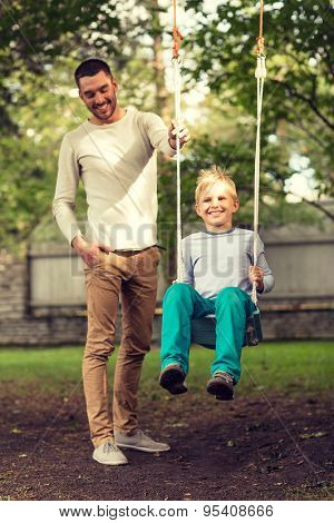family, happiness, generation, home and people concept - happy father and son swinging on teeterboard outdoors