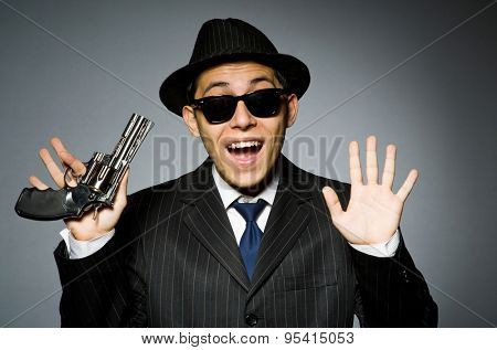 Young man in classic striped costume holding gun isolated on gray