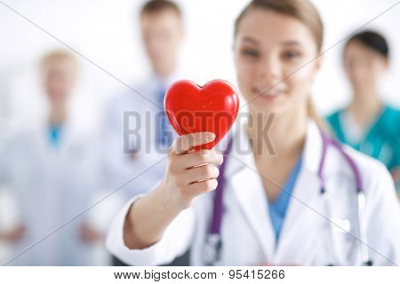 Female doctor with stethoscope holding heart .