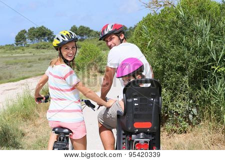 Portrait of happy family riding bikes on a sandy path