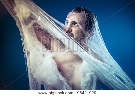 Tangled, naked man trapped in a huge spider web