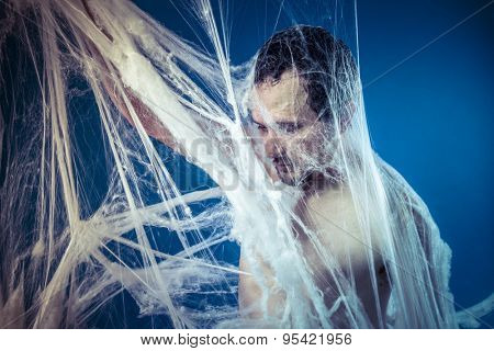 Tangled, naked man trapped in a huge spider web