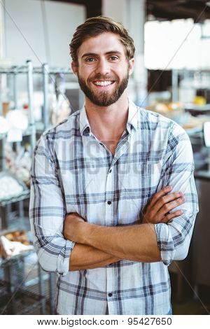 Selfassured waiter smiling in front of his bakery