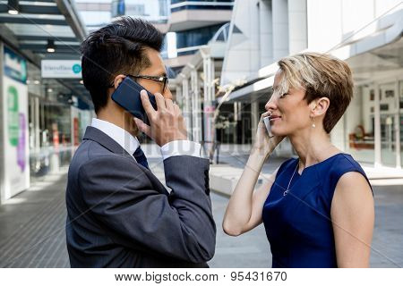 Business people standing in stret with their mobiles