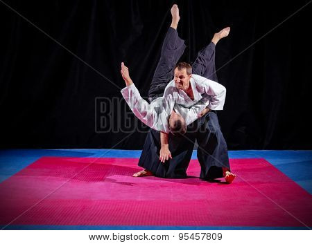 Fight between two aikido fighters on black