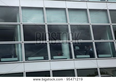 DUSSELDORF, GERMANY - AUGUST 6, 2012: Office clerk using a cell phone seen though the window of an office building in the Hafen District in Dusseldorf, North Rhine-Westphalia, Germany.