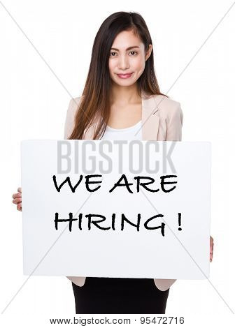 Confident businesswoman holding a poster showing with we are hiring phrases 