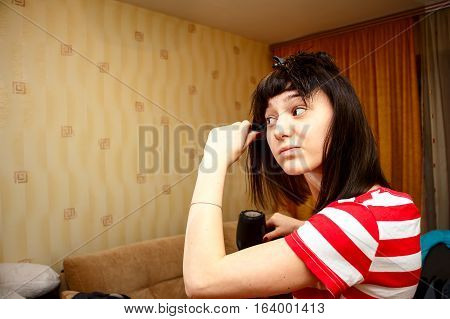 Girl dries hair and makes the hairstyle in her room. She uses the Hairdryer and comb. The home interior 4