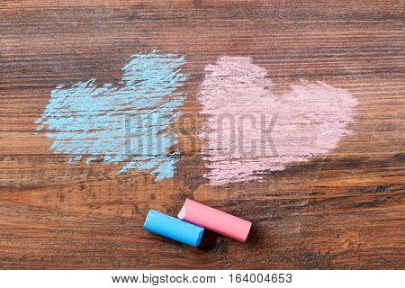 Pink and blue chalk hearts. Chalk sticks on wooden backdrop. Cute art surprise.