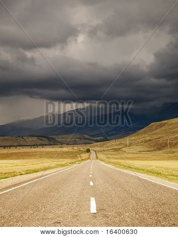 Berglandskap med väg- och mulen himmel