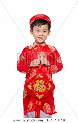 Vietnamese boy cuddling stuffed carp. Portrait of a handsome Asian baby boy on traditional festival costume. Cute little Vietnamese boy in red ao dai dress smiling.
