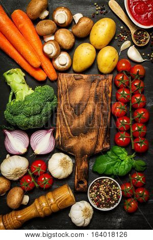 Healthy food background. Healthy food concept with fresh vegetables and ingredients for cooking. Top view with copy space. Dark background.