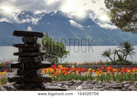 Tower of stones and red tulips near a lake and mountains