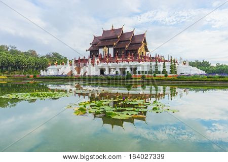 Traditional thai architecture in the Lanna style Royal Pavilion (Ho Kham Luang) at Royal Flora Expo Chiang Mai Thailand in morning mist with blue sky and clouds.