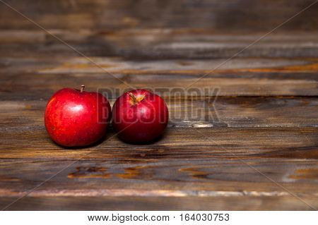 Two red ripe apples on a wooden background close up