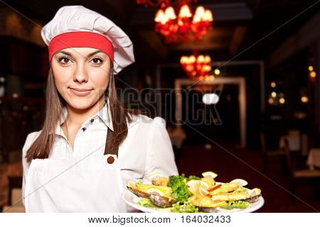 Young attractive female chef with dishes of mussels with fire