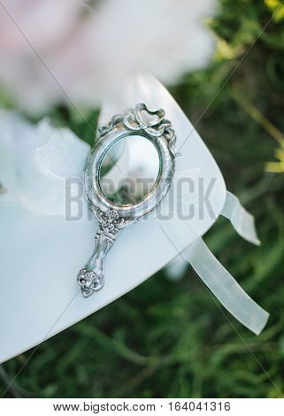 charges of the bride outdoors. vintage silver pocket mirror close up.