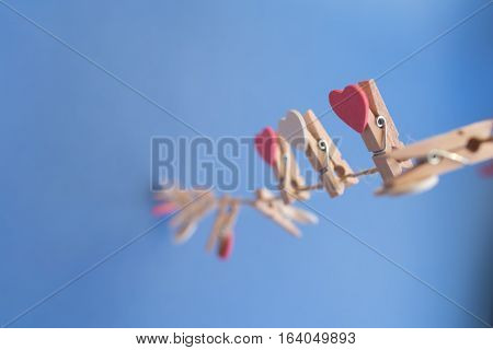 Clothespins with hearts with the twine lay a blue background