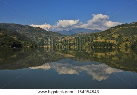 Snow capped peak of the Annapurna range mirroring in lake Begnas Tal. Autumn scene near Pokhara Nepal.