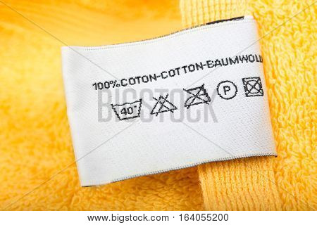 Clothing label with laundry care instructions closeup cloth label on yellow cloth