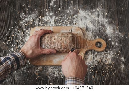 Baking And Cooking Concept Background. Hands Of Baker Closeup Cutting Bread Loaf With Knife On Rusti