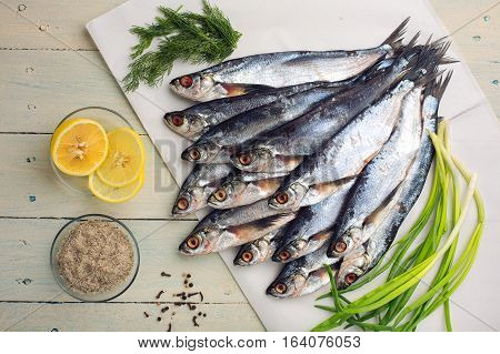 Raw sabrefish slices of lemon herbs and spices. Preparation before cooking on a rustic wooden table