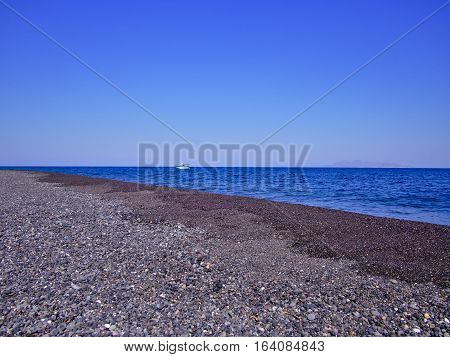 Volcanic pebble beach on Santorinia Island Greece. Greek travel destination poster.