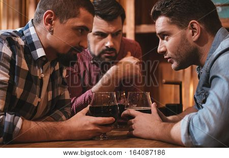 Interesting stories. Handsome attractive nice men leaning forward and exchanging their secrets while drinking beer