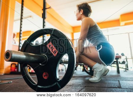 Girl at the gym doing exercise is the deadlift. Sitting near the top of the bar preparing to rise. Sports and active lifestyle. girl in blur.