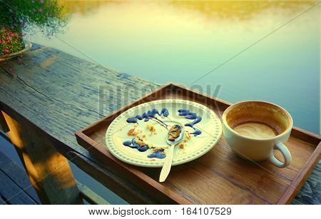 Empty coffee cup and white plate with crumbles of eaten cake and used spoon dirty after finish breakfast.